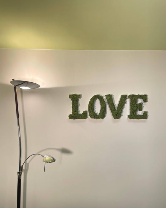 Lettres en métal pour déco LOVE avec lichen stabilisé vert pomme. accroché au mur dans un studio contemporain à coté d'une lumière moderne.